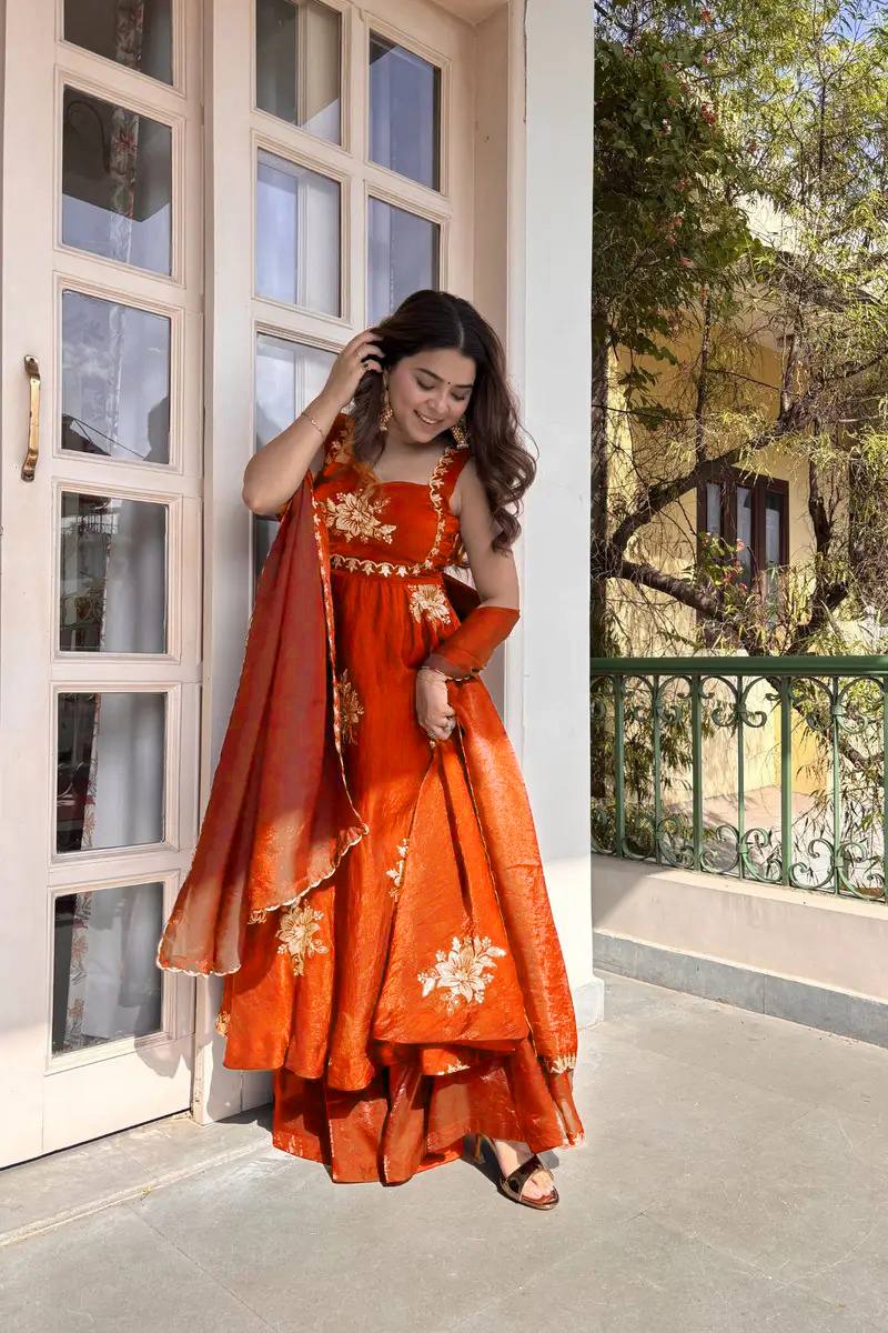 Woman wearing rust orange embroidered Fendy silk Anarkali palazzo set with dupatta twirling outdoor festive wear
