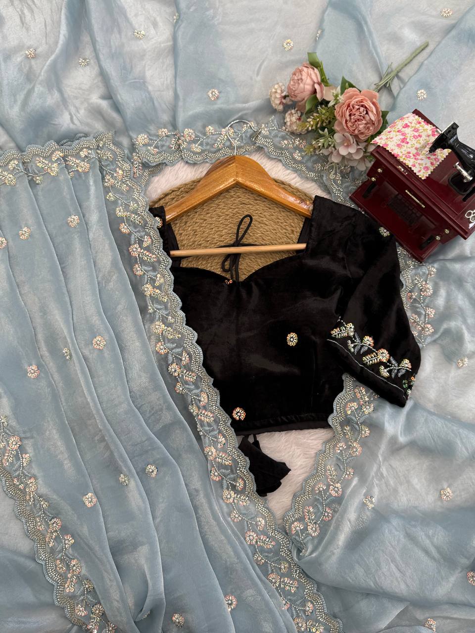 Flat lay of sky blue embroidered saree with velvet blouse and detailed border work