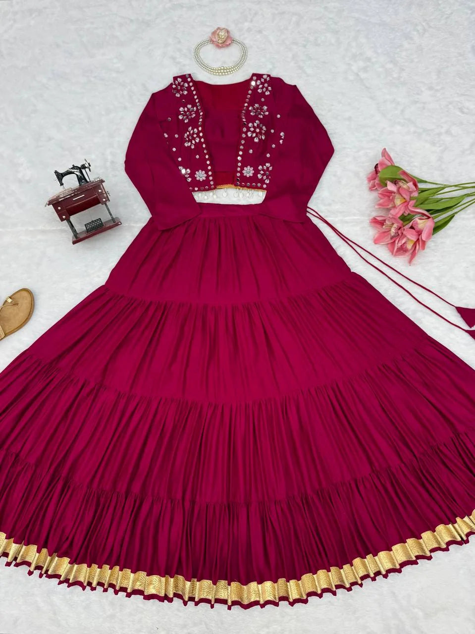 flatlay of wine lehenga with mirror koti set and plain unstitched choli